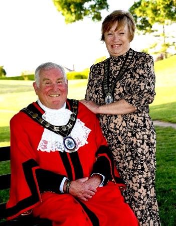 man in mayoral robes seated inf ront of woman in formal dress both smiling directly at camera
