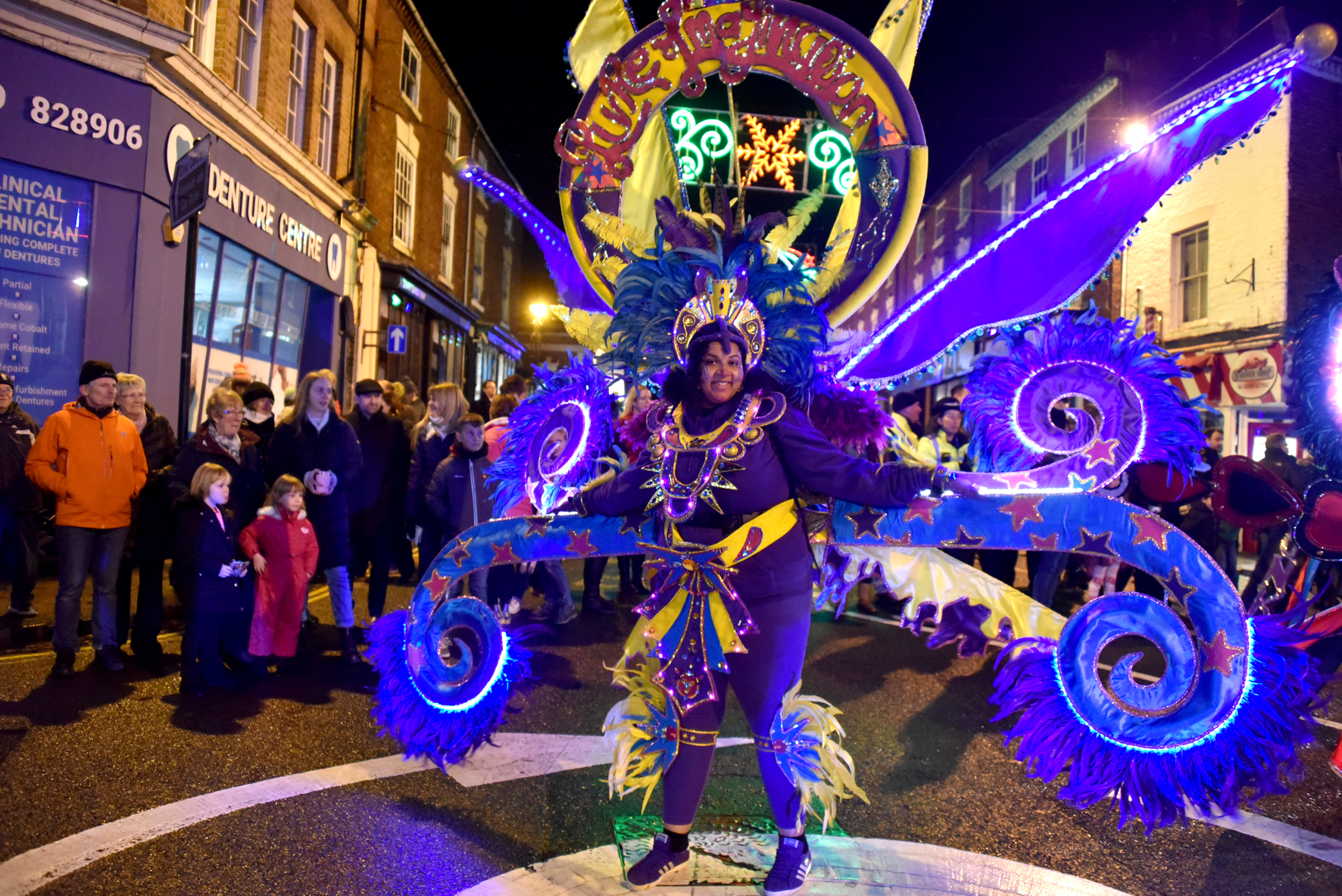 carnival costumed figure smiling, night time parade costume is illuminated